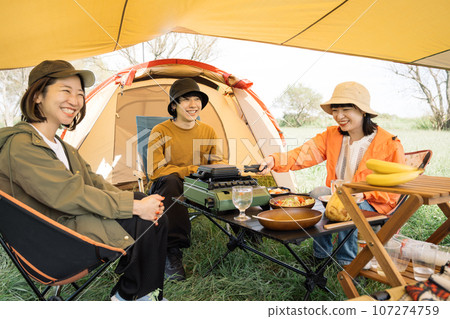 Outdoor image of young men and women enjoying camping Outdoor image of young men and women enjoying camping 107274759