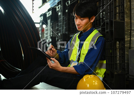 Handsome male worker leaning against rack, checking quantity of storage product in large warehouse Handsome male worker leaning against rack, checking quantity of storage product in large warehouse 107279497
