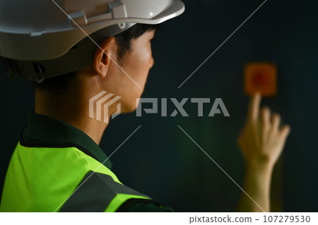 Side view of male workers pressing elevator button in warehouse. Industrial workers concept 107279530