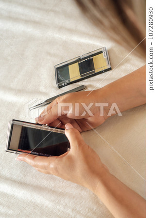 Woman opening palette of fake eyelashes and preparing for lash extension procedure. Tools lying on couch near master. Woman opening palette of fake eyelashes and preparing for lash extension procedure. Tools lying on couch near master. 107280930