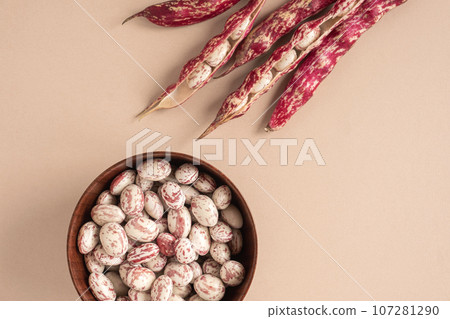 Cranberry beans. Borlotti bean pods in bowl. Top view. Stylish modern food background. Magenta color. Creative foodstuff flat lay. Grocery, dietary backdrop. Advertising, trendy magazine publication. 107281290