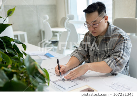 Man architect working with blueprints modeling modern house. 107281345