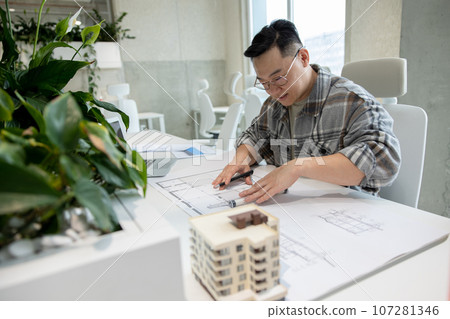 Man architect working with blueprints modeling modern house. 107281346