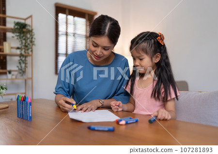Happy family mother and daughter study or draw together at home in living room Happy family mother and daughter study or draw together at home in living room 107281893