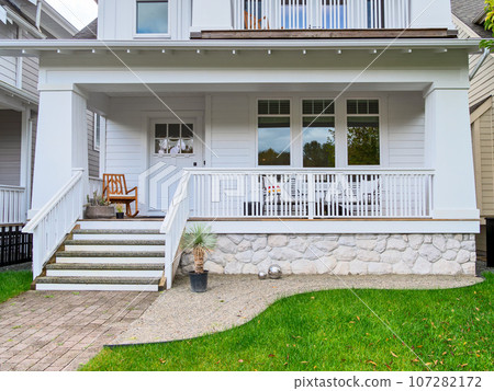 Entrance of detached residential house with rocking chair on front patio 107282172