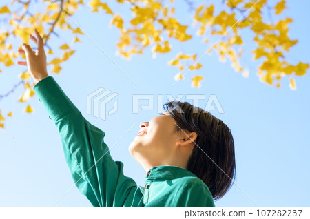 A woman looking at the autumn leaves on a sunny autumn day A woman looking at the autumn leaves on a sunny autumn day 107282237