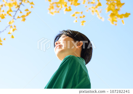 A woman looking at the autumn leaves on a sunny autumn day A woman looking at the autumn leaves on a sunny autumn day 107282241