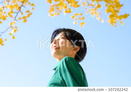 A woman looking at the autumn leaves on a sunny autumn day 107282242