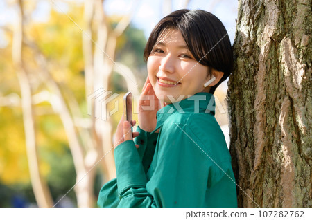 Woman enjoying music in the park Woman enjoying music in the park 107282762