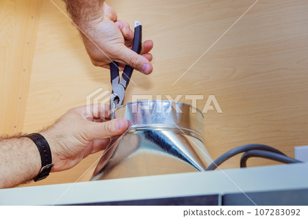 Worker installation placing tube for kitchen hood on kitchen Worker installation placing tube for kitchen hood on kitchen 107283092