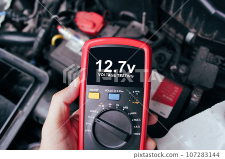 Car battery voltage testing with a digital multimeter by auto technician. 107283144