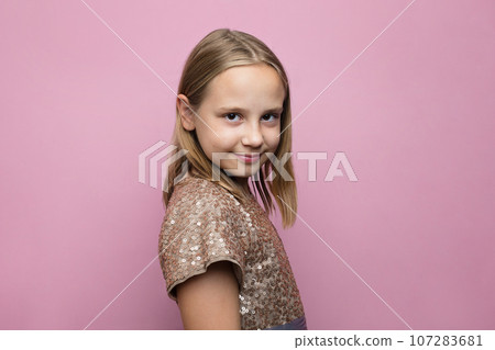 Pretty little child girl with cute smile posing over pink studio wall banner background 107283681