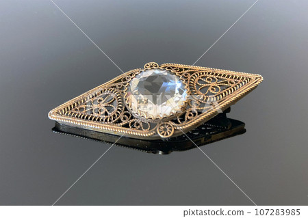 Vintage silver filigree brooch with rhinestone made in 1954 in USSR on dark glossy background Vintage silver filigree brooch with rhinestone made in 1954 in USSR on dark glossy background 107283985