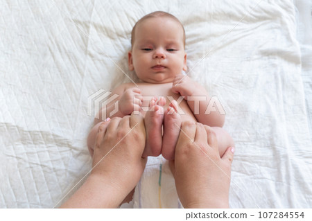 Mother offers relief through baby massage. Concept of natural remedies for colic 107284554