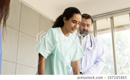 Doctor and physiotherapist doing a rehabilitation recovery for Hispanic patient girl. Healthcare and medical service at the hospital. The medical exam and therapy for body pain injury. 107285865