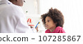 African American dentist explaining to mixed-race afro child how to brush teeth. The doctor and healthcare concept for children. 107285867
