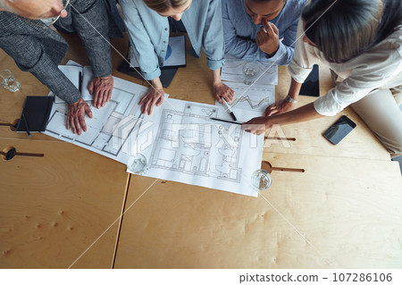 Top view of professional design engineers working with project documents in modern office Top view of professional design engineers working with project documents in modern office 107286106
