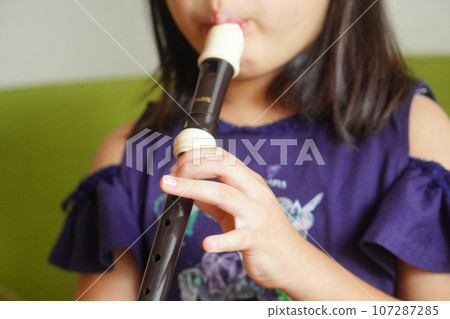 A fourth grade elementary school girl plays the recorder. 107287285
