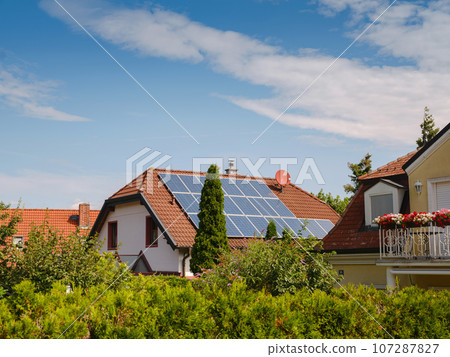 Solar photovoltaic panels on house roof. Modern country house with self-sustaining energy system. Suburb of Vienna, Austria. Idea harnessing clean and sustainable energy, saving money on electricity Solar photovoltaic panels on house roof. Modern country house with self-sustaining energy system. Suburb of Vienna, Austria. Idea harnessing clean and sustainable energy, saving money on electricity 107287827