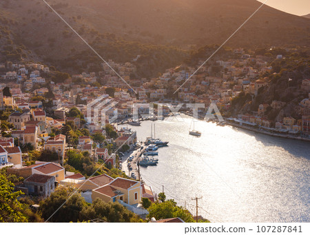 Symi Island, Greece. Greece islands holidays from Rhodos in Aegean Sea. Colorful neoclassical houses in bay of Symi. view of main bay of island, where tourist ferries and yachts moor 107287841
