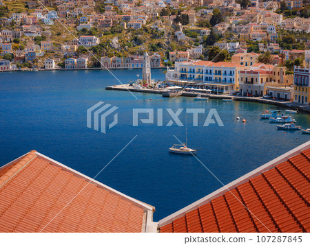 Symi Island, Greece. Greece islands holidays from Rhodos in Aegean Sea. Colorful neoclassical houses in bay of Symi. Holiday travel background. view from hill Symi Island, Greece. Greece islands holidays from Rhodos in Aegean Sea. Colorful neoclassical houses in bay of Symi. Holiday travel background. view from hill 107287845