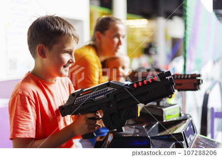 Happy kids playing a shooting game on slot machines at an amusement park 107288206