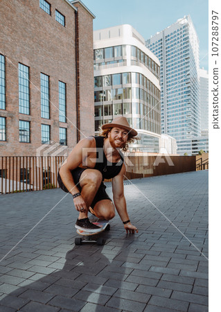 Vertical shot of the young skilful skater performing fast skateboard riding at urban city street  107288797