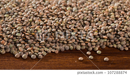 Raw lentil background on wooden surface, nutritious food Raw lentil background on wooden surface, nutritious food 107288874