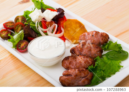 Tasty balkan minced meat kebapcheta served with onion, tomatoes, lettuce Tasty balkan minced meat kebapcheta served with onion, tomatoes, lettuce 107288963
