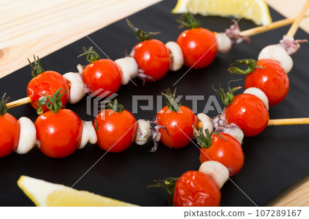 Baked mini calamari and cherry tomatoes on skewers 107289167