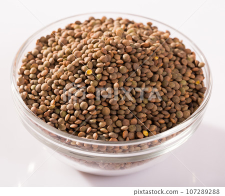 Lentils in a glass cup on a white surface 107289288