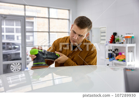 Car detailing and polishing concept, man working with orbital polisher 107289930