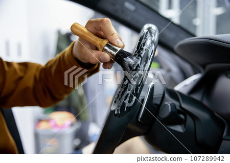 Car detailing service, closeup worker hands cleaning steering wheel Car detailing service, closeup worker hands cleaning steering wheel 107289942