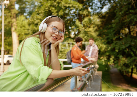 Dreamy teenage female student in headphones relaxing listening music 107289995