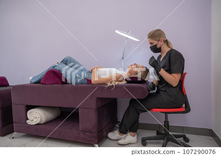 Caucasian woman on eyelash extension procedure. Caucasian woman on eyelash extension procedure. 107290076