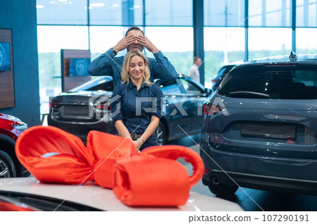 A bearded man makes a gift to his beloved wife in the form of a new white car. A bearded man makes a gift to his beloved wife in the form of a new white car. 107290191