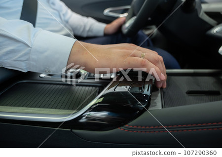 Close-up of a man's hands on the automatic transmission of a modern car.  107290360