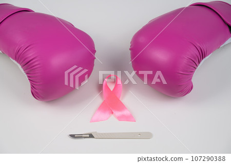 Pink boxing gloves, a surgical scalpel and a pink ribbon on a white background. The concept of fighting breast cancer.  107290388