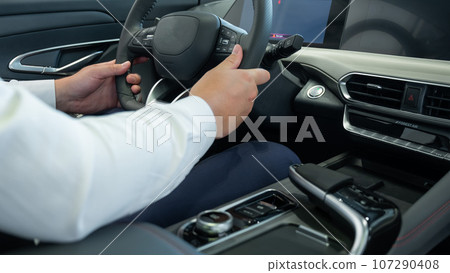 Close-up of a man's hands on the steering wheel of a modern car. Close-up of a man's hands on the steering wheel of a modern car. 107290408