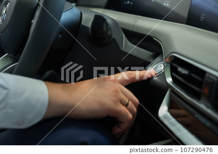 A man presses the car engine start button.  107290476