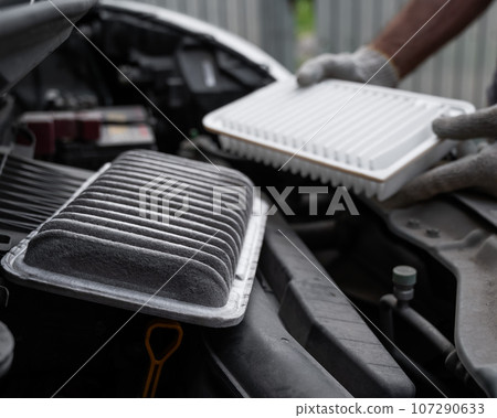 The master changes the air filter in the car engine.  107290633