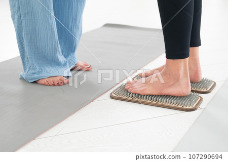 Caucasian woman stands on sadhu boards with therapist support. 107290694