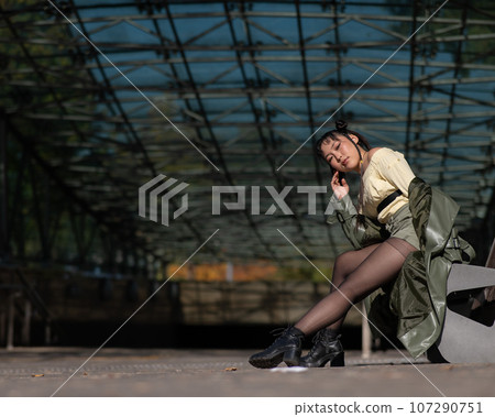 A young Asian woman sits on a bench at the subway exit. A young Asian woman sits on a bench at the subway exit. 107290751