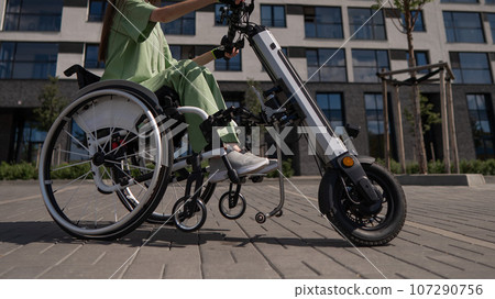 A woman in a wheelchair with an assistive device for manual control. Electric handbike.  107290756
