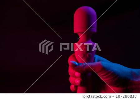 Woman holding a vibrator in neon pink and blue light. 107290833