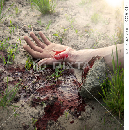 Bloodied hand lies on the ground 107291014