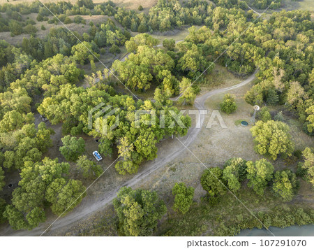 Whitetail Campground on the shore of Dismal River in Nebraska National Forest, late summer dawn aerial view with SUV vehicle 107291070
