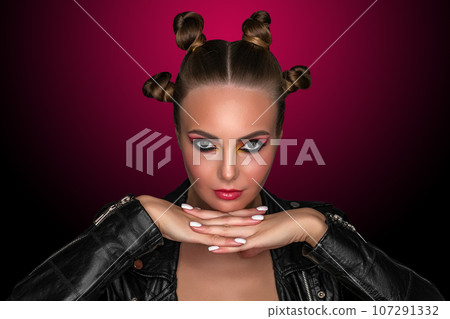Portrait of a young sassy girl with blond hair in the studio on a pink background. Portrait of a young sassy girl with blond hair in the studio on a pink background. 107291332