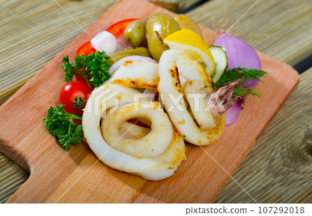 Cooked tasty squid rings with potatoes and fresh vegetables and greens 107292018