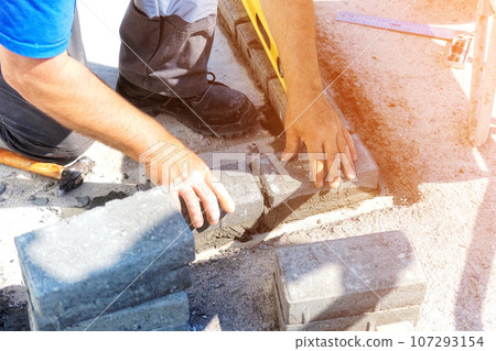 Mason lays out brickwork from gray bricks. Hands of builder with trowel close-up. Man works at Mason lays out brickwork from gray bricks. Hands of builder with trowel close-up. Man works at 107293154